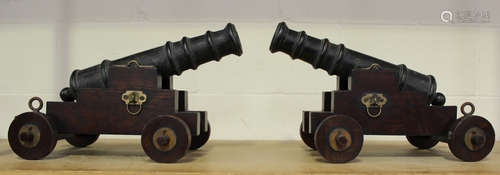 A pair of ornamental bronze cannon, the patinated cast bronze barrels raised on oak and brass