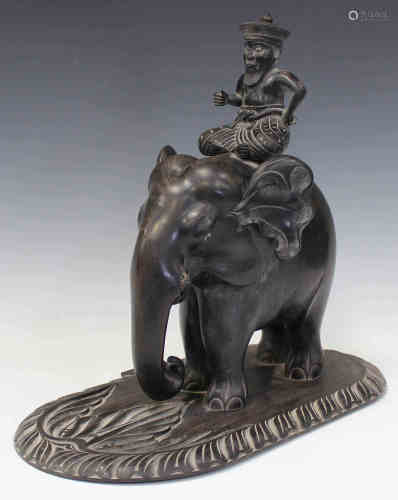 An early 20th century Ceylonese carved ebony model of an elephant and rider, raised on a foliate