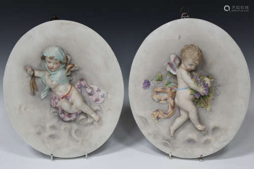 A pair of French porcelain oval wall plaques, circa 1900, allegorical of Autumn and Winter, each