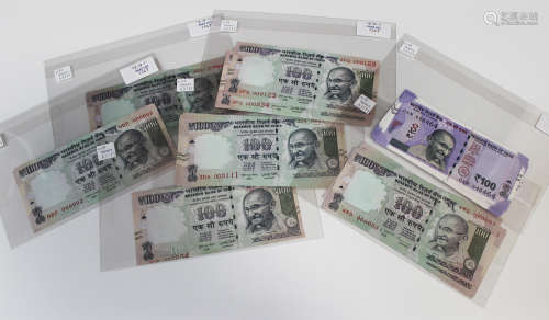 A collection of Indian banknotes, including a one hundred rupees, shifting number error, and a