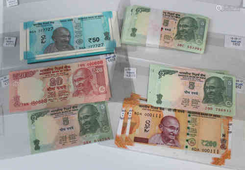A collection of Indian banknotes, including a consecutive run of one hundred five rupees, dated