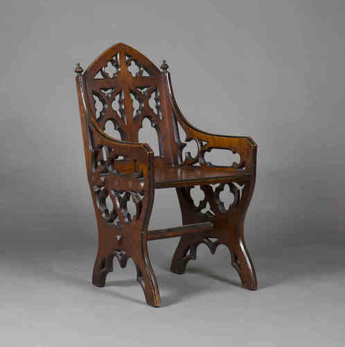 A late Victorian Gothic Revival oak and ebonized armchair, the arched back and shaped sides with