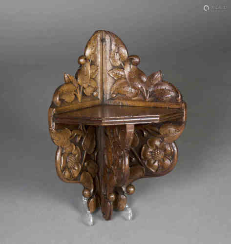 A late 19th/early 20th century Arts and Crafts oak corner shelf, finely carved with Tudor style