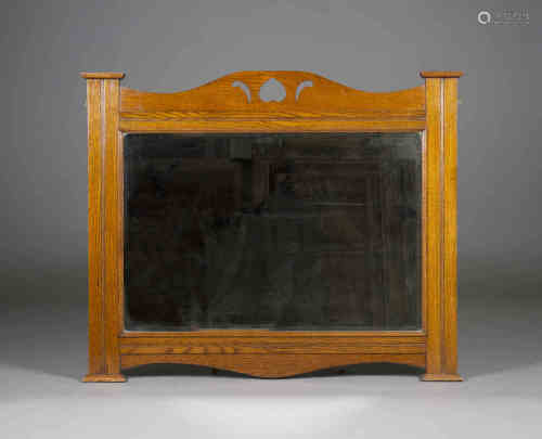 An Edwardian Arts and Crafts oak overmantel mirror, in the manner of Liberty & Co, the shaped top