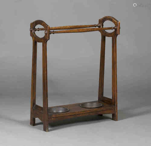 An early 20th century Arts and Crafts oak umbrella stand, the pierced ends united by turned supports