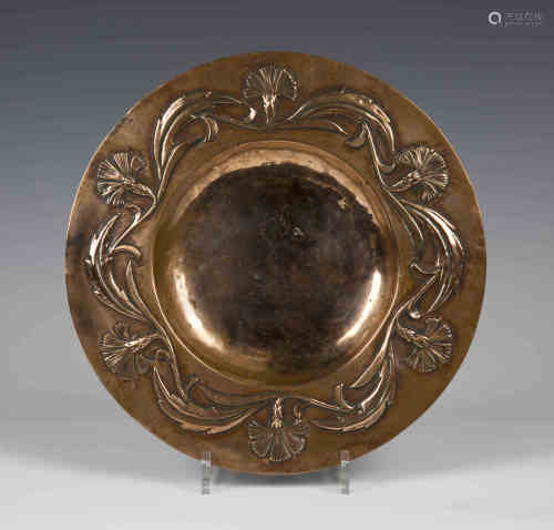 An early 20th century Arts and Crafts copper circular dish, the raised rim finely worked with a band