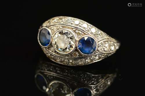 AN EARLY TO MID 20TH CENTURY SAPPHIRE AND DIAMOND BOMBE STYLE RING, centring on an early brilliant