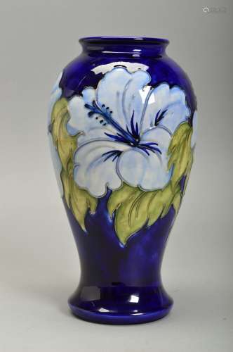 A MOORCROFT HIBISCUS DESIGN VASE, of baluster form, pale blue flowers on a dark blue ground,