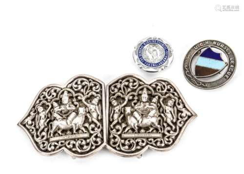 A vintage Indian silver nurse's belt buckle, together with two nurse's badges (4)