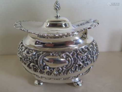 A very pretty embossed silver sugar casket, standing on four bun feet, hinged pagoda lid, with