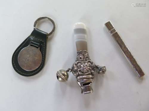 A key ring with silver golfing plaque, a silver rattle teether, and a silver cased nail file