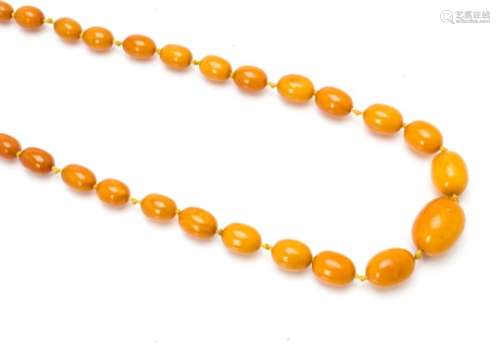A large graduated, knotted amber string necklace, the toffee coloured beads with largest 3cm x 2.3cm