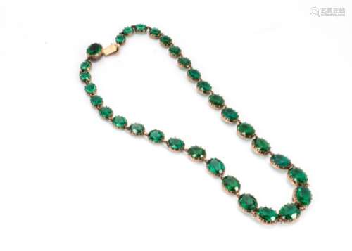 A late 19th/early 20th Century yellow metal green paste necklace, the graduated oval cut glass