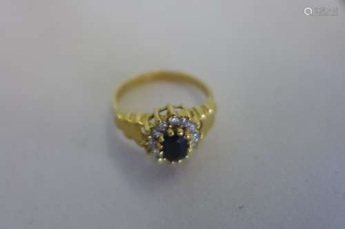 An 19ct yellow gold sapphire and diamond ring, single sapphire with twelve diamonds surrounding it