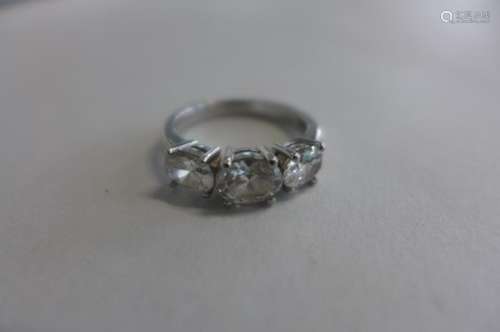 A platinum three stone diamond ring, the central oval diamond 0.64 carat, flanked either side by