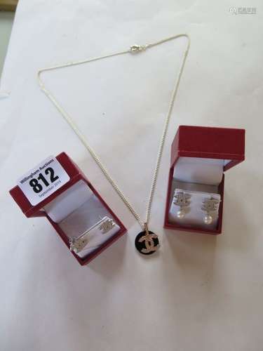 A silver Chanel style pendant necklace and two pairs of similar earrings