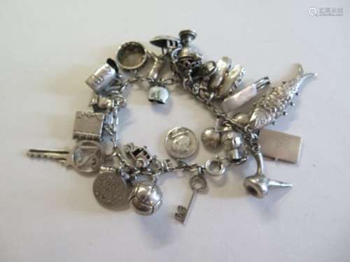 A silver charm bracelet with 24 charms, approx 1.8 troy oz - in good condition, clasp working