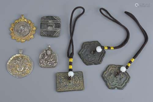 A group of seven bronze and white metal pendants