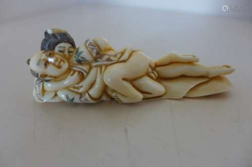 A Japanese Meiji period, early 1900's signed carved ivory okimono of an entwined couple, incised and