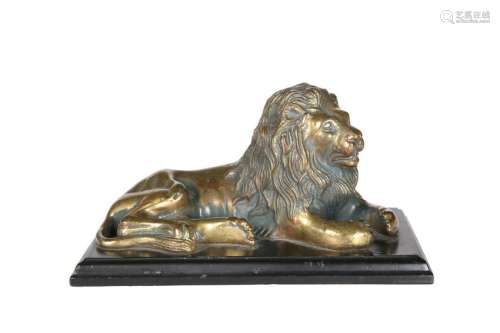 A GILDED BRONZE MODEL OF A RECUMBENT LION, on a wooden