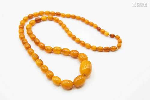 AN AMBER COLOURED BEAD NECKLACE, of sixty four