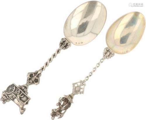 (2) gelegenheidslepels zilver.Beiden met gevlochten steel en dolfijn ornamenten met daarop o. a. een