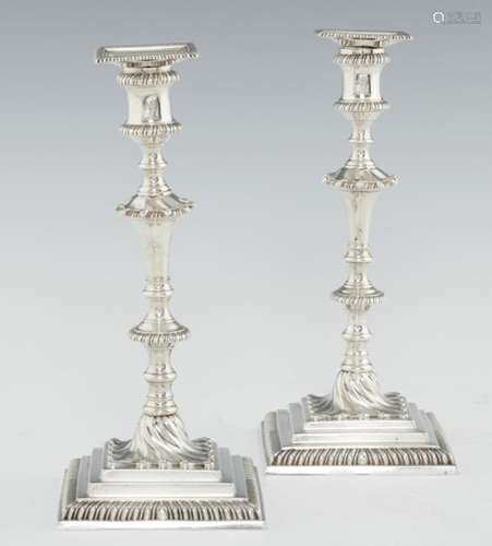 A PAIR OF GEORGE III GADROONED SILVER CANDLESTICKS with waisted sconce, swirl base and stepped