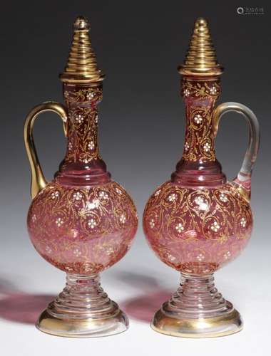 A PAIR OF ENAMELLED AND GILT CRANBERRY GLASS PEDESTAL EWERS AND MATCHING STOPPERS, EARLY 20TH C 27cm