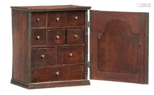 A GEORGE II OAK SPICE CUPBOARD, C1750-70 with breakarched, panelled door and fitted with nine