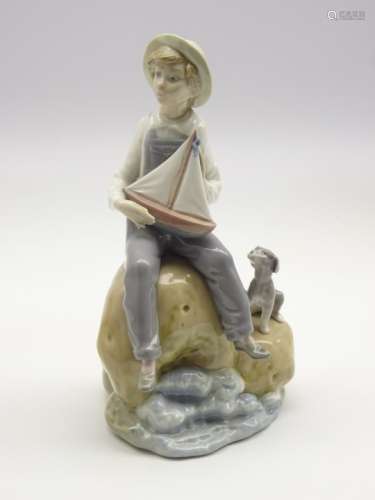 Lladro figure of a boy holding a pond yacht and seated on a rock No.