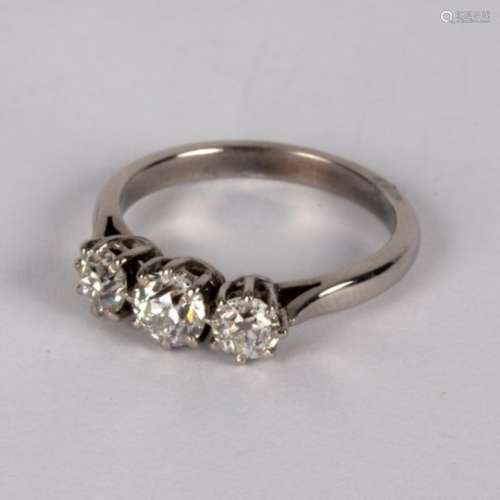 A diamond three-stone ring, claw set in precious white metal, the central stone approximately 0.