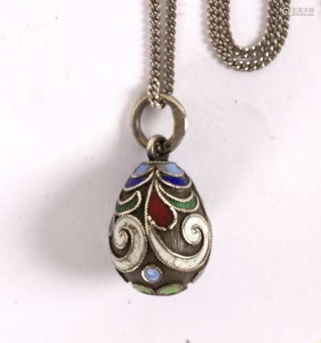 A Russian silver and enamel egg form pendant decorated scrolls and dots in coloured enamels,