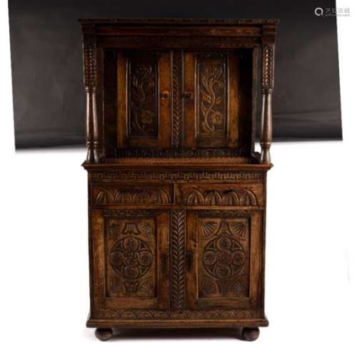 A carved oak cabinet, the upper and lower sections enclosed by panel doors,