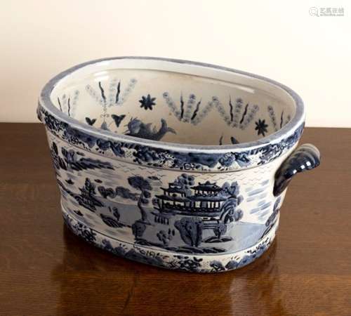 A large blue and white willow pattern two-handled foot bath,