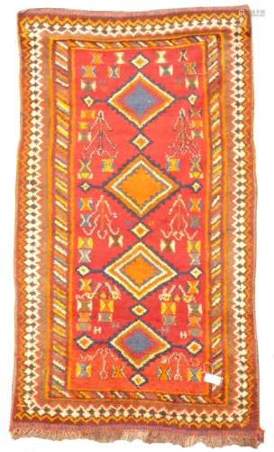 Tribal woollen red ground rug, quadruple lozenge medallion, stylised motifs, repeating boarder,