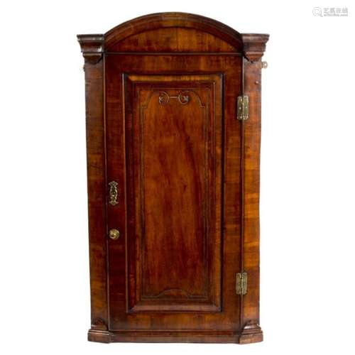 An early 18th Century walnut arch-top corner cupboard, enclosed by a carved panel door,