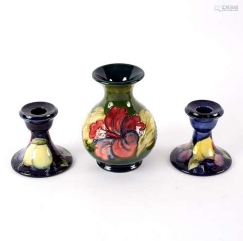 A Moorcroft Hibiscus pattern vase, 14cm high and a pair of Moorcroft Wisteria pattern candlesticks,