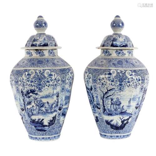 A large pair of Delftware blue and white vases and covers painted scenes representing the four