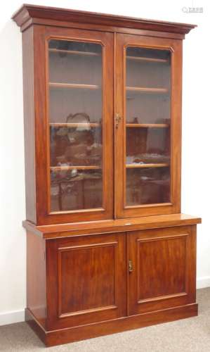 Victorian mahogany bookcase on cupboard, projecting cornice above two glazed doors,