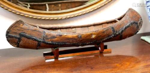 A scale model of a Native American birchbark canoe on a later stand,