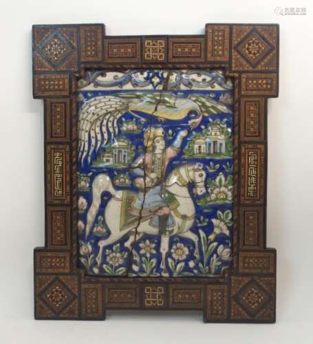 A PERSIAN POLYCHROME MOULDED POTTERY TILE decorated with a prince on horseback feeding a bird and