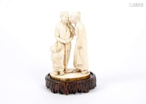 A late 19th Century Japanese carved ivory figure group, of two men conversing whilst a child