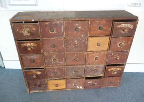 A stained pine chemist cabinet, containing a bank of twenty-five drawers, with turn around