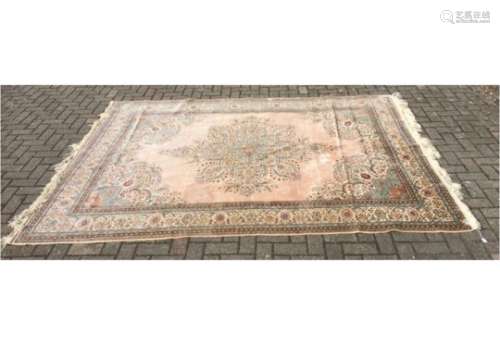 A large 20th Century silk rug, with a floral border and central motif on a pale silk ground and