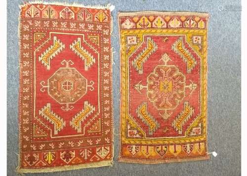 Two Caucasian woollen mats, each with central hooked medallion on red field, stylized borders, the