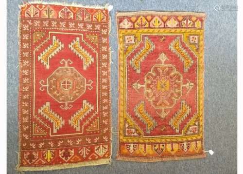 Two Caucasian woollen mats, each with central hooked medallion on red field, stylized borders, the