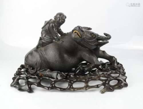 A fine Chinese carving of a water buffalo on stand, with figure riding on its back.