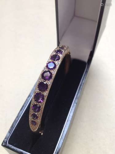 A 9ct GOLD AMETHYST AND DIAMOND CARVED HINGED BANGLE COMPLETE WITH FIGURE OF EIGHT SAFETY CLASP,