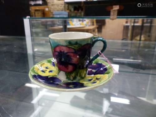 A WILLIAM MOORCROFT PANSY PATTERN COFFEE CUP AND SAUCER