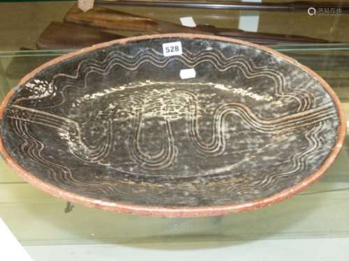 AN ABUJA OVAL PLATTER THE DEEP BROWN GLAZE RAKED WITH FOUR WAVY LINES AROUND THE RIM AND